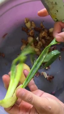 Genç adam mutfakta yeşil soğan pişiriyor..