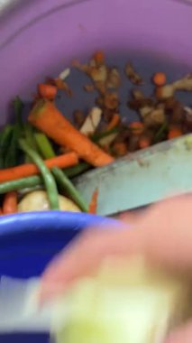 Bir adam kirli bir kaseyi havuçla yıkıyor.