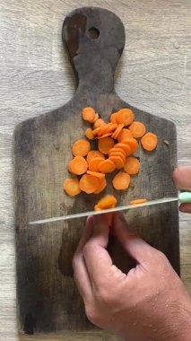 Kesme tahtasındaki bir bıçakla yuvarlak bir tahtayı kesiyor.