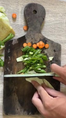 Aşçı sebzeleri ahşap bir masada keser.