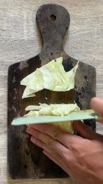 Kesme tahtasında bıçakla lahana kesmek.