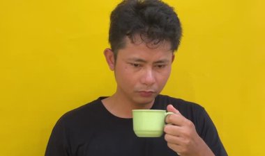 Elinde kahve ya da çay olan genç bir adam. Yeşil arkaplanda izole