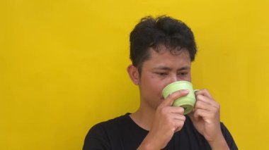 Asyalı genç adam sıcak içecek içiyor, beyaz arka planda izole edilmiş..