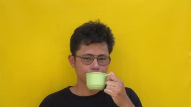 Genç Asyalı bir adam beyaz arka planda kahve içiyor, yakın plan..