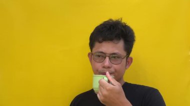 Kahve ya da çay içen Asyalı genç adamın portresi..