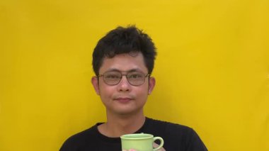 Gözlüklü ve sarı tişörtlü Asyalı adam.