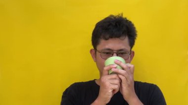 Asyalı adam fincanda çay içiyor.