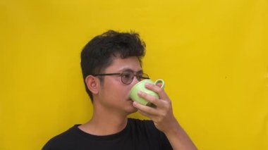 Asyalı yakışıklı bir adam, elinde sarı bir fincan kahve.