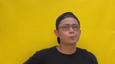 Siyah gözlüklü, sarı gömlekli Asyalı adam.