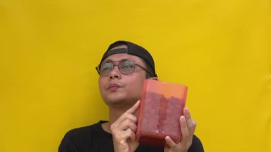 Kitabı tutan gözlüklü ve sarı şapkalı genç adam..