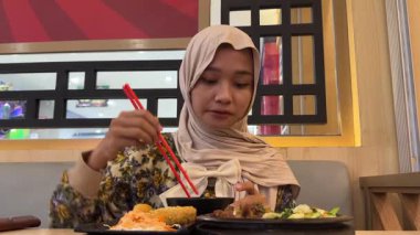 Kızarmış tavuklu pilav yiyen Asyalı kadın.