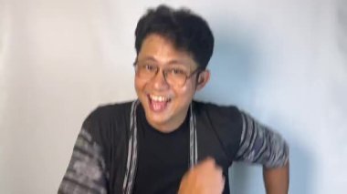 Asyalı bir adamın portresi zaferi kutluyor, elleri havada, beyaz arka planda soyutlanmış..