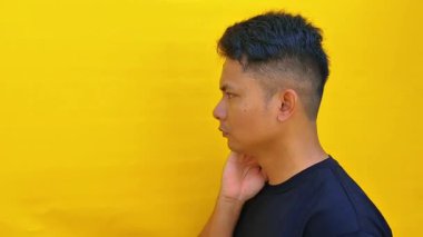 Ciddi ve yoğun bir yüz ifadesi olan ve doğrudan kameraya bakan Asyalı genç bir adamın portresi. Huysuz ve duygusal bir görüntüyle yakın çekim..