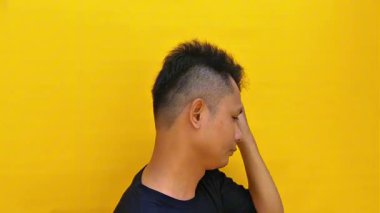 Ciddi ve yoğun bir yüz ifadesi olan ve doğrudan kameraya bakan Asyalı genç bir adamın portresi. Huysuz ve duygusal bir görüntüyle yakın çekim..