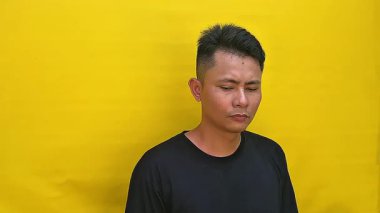 Ciddi ve yoğun bir yüz ifadesi olan ve doğrudan kameraya bakan Asyalı genç bir adamın portresi. Huysuz ve duygusal bir görüntüyle yakın çekim..