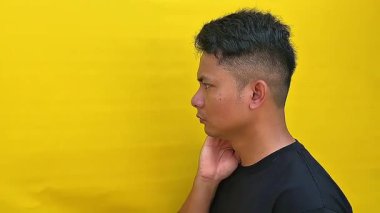 Ciddi ve yoğun bir yüz ifadesi olan ve doğrudan kameraya bakan Asyalı genç bir adamın portresi. Huysuz ve duygusal bir görüntüyle yakın çekim..