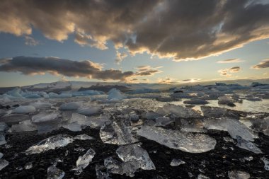 Buzullar gün batımında Jokulsarlon buzulunun kıyısında kıyıya vurdu.
