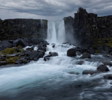 Kayalık ortamda Oxarafoss şelalesi ve güney İzlanda 'da bulutlu gökyüzü