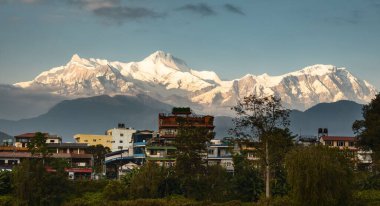 Öğleden sonra Himalaya dağlarının panoramik manzarası ve Nepal 'deki Pokhara kasabasının çatıları.