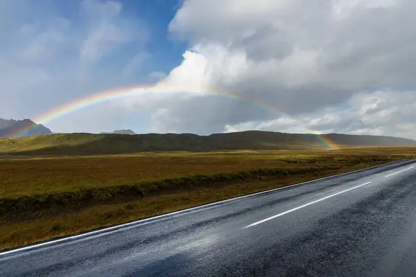 Yol kenarındaki renkli gökkuşağı kırsal İzlanda tepelerinin üzerinden gündüz boyunca