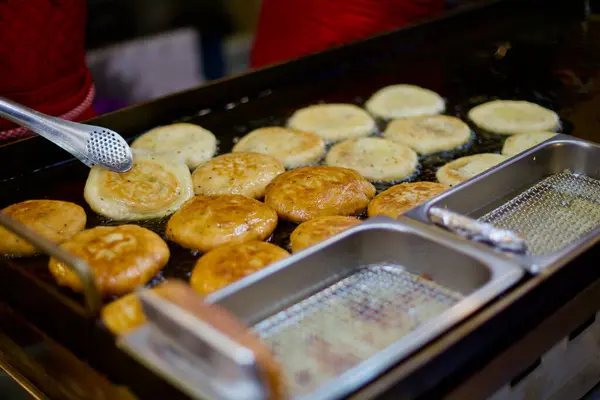 Geleneksel bir markette popüler bir Kore sokak yemeği olan Hotteok 'u ustalıkla kızartıp havayı bu leziz kreplerin kokusuyla dolduran bir satıcı..