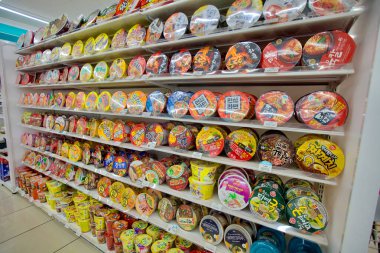 Ulsan, Güney Kore - 3 Mart 2020: Kore 'de popüler bir hızlı yemek seçimini sergileyen, bir markette raflarda sergilenen, gözle görülür yuvarlak kapaklı hazır ramen tabağı..