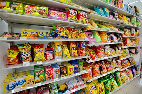 Ulsan, Güney Kore - 3 Mart 2020: Bir markette iyi stoklanmış abur cubur bölümü, bir dizi cips, patlamış mısır, kurabiye ve diğer atıştırmalıkların yer aldığı, kolay seçim için davetiye ile sergilenen.