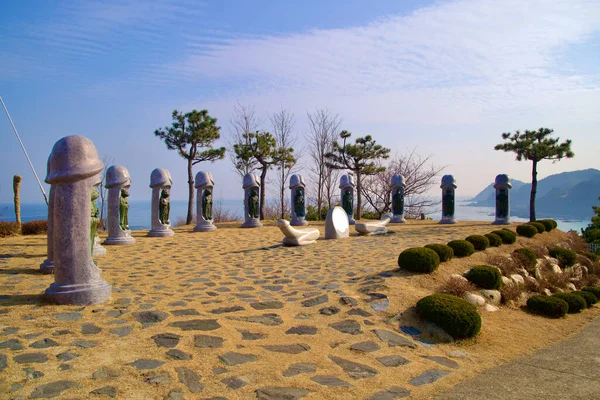 Samcheok City, South Korea - December 28, 2023: Intriguing two-meter tall stone penis sculptures with embedded Chinese zodiac animals, set in a courtyard against a backdrop of blue sky and the East Sea.
