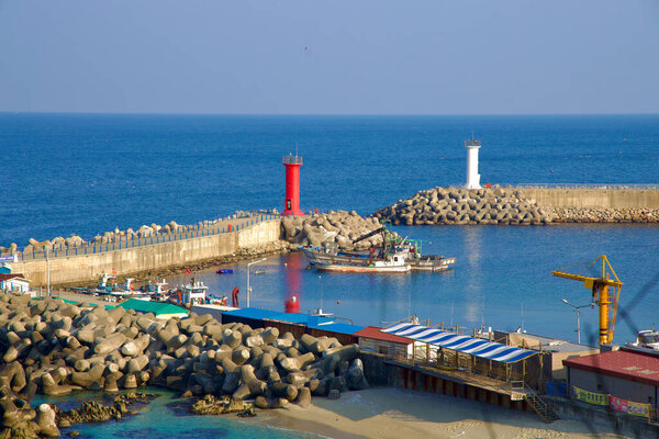 Samcheok City, South Korea - December 28, 2023: At Galnam Port, a small market sits at the end of the breakwater, near the red and white lighthouses, against the backdrop of the East Sea.