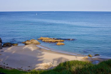 Yangyang İlçesi, Güney Kore - 30 Temmuz 2019: Dongho Sahili yakınlarında sakin bir kumsal kıyısı, kıyıya yakın sularda kayalar yuva yapmış, Doğu Denizi ufukta pürüzsüz bir şekilde birleşirken.