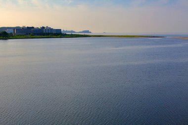 Yangyang İlçesi, Güney Kore - 30 Temmuz 2019: Sakin suların Doğu Denizi ile buluştuğu Yangyang Namdae Akıntısı 'nda, oteller ve kumlu bir çukur ağızla birleştiği pitoresk bir günbatımı manzarası.