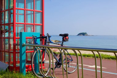 Goseong County, South Korea - July 30, 2019: A bike securely parked on a rack beside the Bongpo Beach Certification Center, with the serene Jukdo Island visible on the horizon in the East Sea, marking a moment of adventure and exploration on a summer clipart