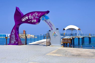 Goseong County, Güney Kore - 31 Temmuz 2019: Daejin Deniz Port Parkı 'nın tuhaf girişi, ziyaretçileri limanın ve Doğu Denizi' nin panoramik manzaraları için su üzerinden geçen mor bir balina kuyruğu tarafından işaretlenmiştir..