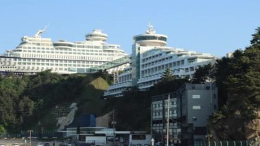 Gangneung City, Güney Kore - 18 Mayıs 2024: Jeongdongjin Limanı 'ndaki uzun gemi şekilli Balık Çorbası Restoranı' na hareket eden Sun Cruise Resort 'un yolcu gemisi şekilli binalarını görüntüleyen bir sol çekim.