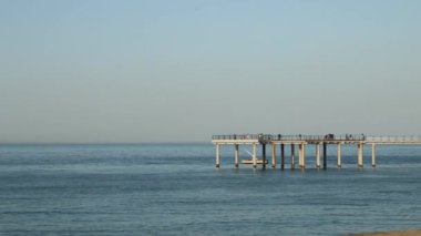 Gangneung City, Güney Kore - 18 Mayıs 2024: Doğu Denizi ve Jeongdongjin Sahili 'ni gün batımına yakın gösteren bir video. Video, önce deniz boyunca uzanan bir gözlemevine, sonra Jeongdongjin Limanı 'na ve sonra da gemi şeklinde uzun bir restorana gidiyor..