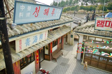 Ulsan, Güney Kore - 17 Mart 2024: Jangsaengpo Balina Kültür Köyü 'nün hareketli bir hava manzarası, geleneksel Kore kiremitli çatıları, renkli afişler ve Çin restoranı da dahil olmak üzere çeşitli dükkanlar sergileniyor. Sahne canlı bir atmosfer yakalıyor.