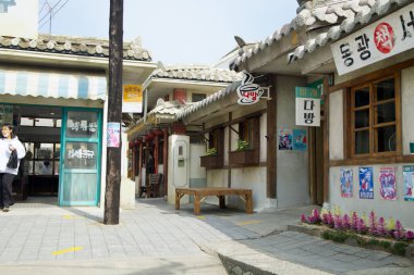 Ulsan, Güney Kore - 17 Mart 2024: Jangsaengpo Balina Kültür Köyü 'nde tarihi bir kitapçı ve kafe, dış yüzeyinde eski çizgi roman ve filmlerin posterleri yer alıyor. Tek katlı binanın geleneksel olarak Kore fayanslı çatısı var..