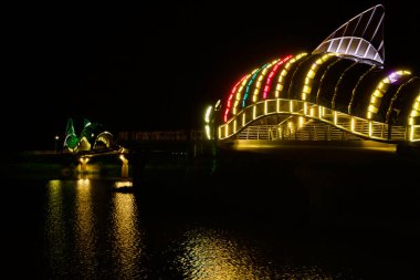 Uljin, Güney Kore - 18 Mayıs 2024: Aydınlatılmış Uljin Tatlı Balık Köprüsü 'nün Namdae Akıntısı' nın sularını yansıtan LED ışıklı balık heykelleri, canlı renkleri ve mimari güzelliği yansıtan gece görüntüsü.