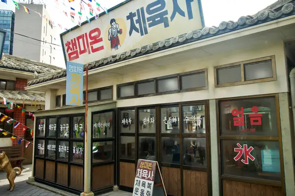 stock image Ulsan, South Korea - March 17, 2024: The exterior of a vintage sportswear store at Jangsaengpo Whale Culture Village, complete with colorful banners and traditional Korean tiled roof. The storefront reflects mid-20th century Korean design.