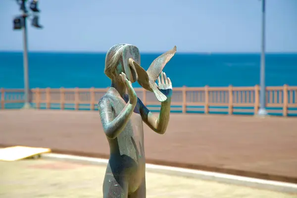stock image Samcheok, South Korea - May 18th, 2024: A close-up view of a bronze sculpture depicting a serene interaction between a human figure and a bird, situated at the Beach Sculpture Park along Isabu Road. This piece of art, set against the stunning backdro