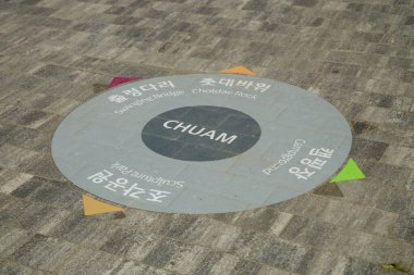 Donghae City, South Korea - May 18th, 2024: A directional sign on the pavement in Chuam, guiding visitors to various attractions including the Swinging Bridge, Chotdae Rock, Sculpture Park, and more. clipart