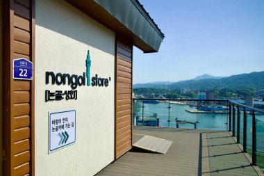 Donghae City, South Korea - May 18th, 2024: The Nongol Store on Nongoldam Street provides a panoramic view of Mukho Port and the surrounding mountains, blending modern design with scenic beauty. clipart