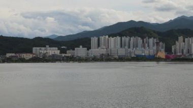 Sokcho, Güney Kore - 28 Temmuz 2024: 13 saniyelik bir 4K ekran görüntüsü, Seorak Grand Köprüsü 'nden seyredildiği gibi dingin Cheongcho Gölü' nü, Sokcho 'nun şehir manzarası ve arka plandaki dağları yakalar..