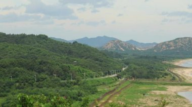 Goseong County, Güney Kore - 28 Temmuz 2024: Kuzey Kore 'deki Goseong Birleşme Gözlemevi' nden bakıldığında arka planda sakin kıyı manzarası ve Kumgang Dağı 'nın soldan sağa dönük bir görüntüsünü içeren 4K video.