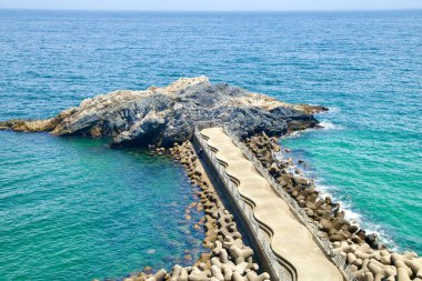 Uljin County, South Korea - July 27th, 2024: A scenic view of Gatbawi Rock and the adjacent concrete walkway extending into the East Sea, offering a popular spot for fishing and coastal sightseeing in Deunggi Mountain Park. clipart