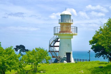 Uljin County, South Korea - July 27th, 2024: A close-up view of a lighthouse in Deunggi Mountain Park, surrounded by greenery and overlooking the East Sea, offering a peaceful and picturesque setting. clipart