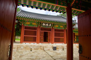 Samcheok, South Korea - July 29, 2024: A view through the partially open traditional gates leading to a beautifully ornate building in the Jukseoru Pavilion complex, featuring colorful wooden architecture and a stone courtyard in Gangwon Province. clipart