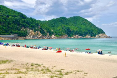 Yonghwa Plajı, Samcheok, Kore, plaj, kum, dağlar, rahatlama, şemsiyeler, okyanus, deniz, turkuaz suyu, yaz, seyahat, doğa, macera, manzara, açık hava, turizm, aile dostu, barışçıl, plaja gidenler, manzara, kıyı, Güney Kore, tatil, 