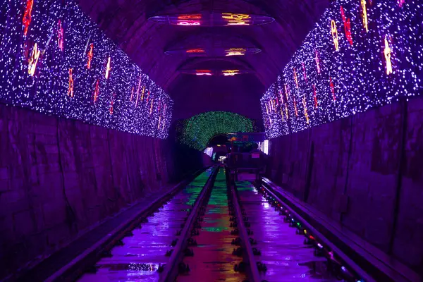 stock image Samcheok, South Korea - July 29th, 2024: A mesmerizing view of vibrant neon lights illuminating the Fantasy Tunnel as riders glide through the Samcheok Marine Rail Bike route, creating a vivid and electrifying atmosphere.