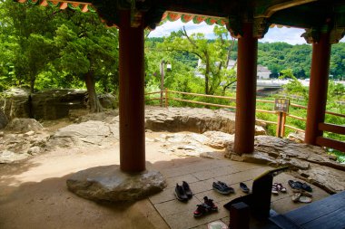 Samcheok, South Korea - July 29, 2024: Shoes neatly removed at the entrance of Jukseoru Pavilion, in accordance with traditional customs, as the pavilion opens out onto natural rocky terrain and lush greenery in Gangwon Province. clipart